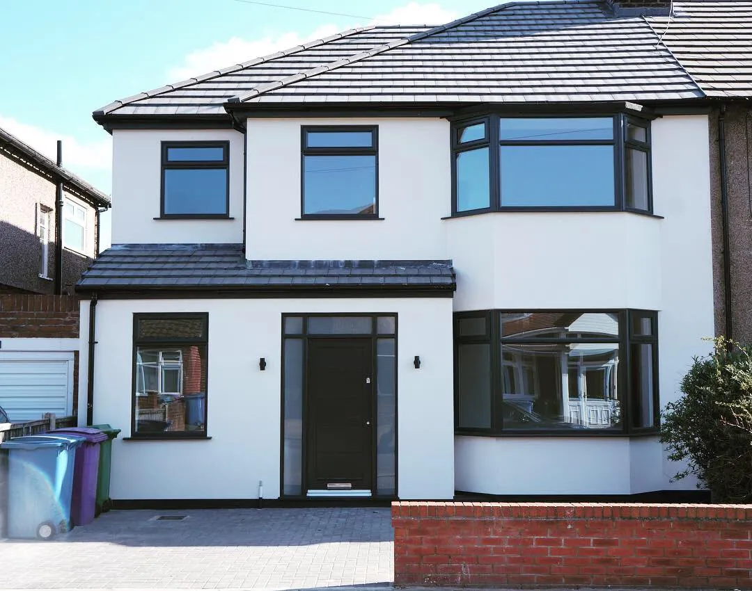 Completed two-storey house extension with white render and dark framed windows